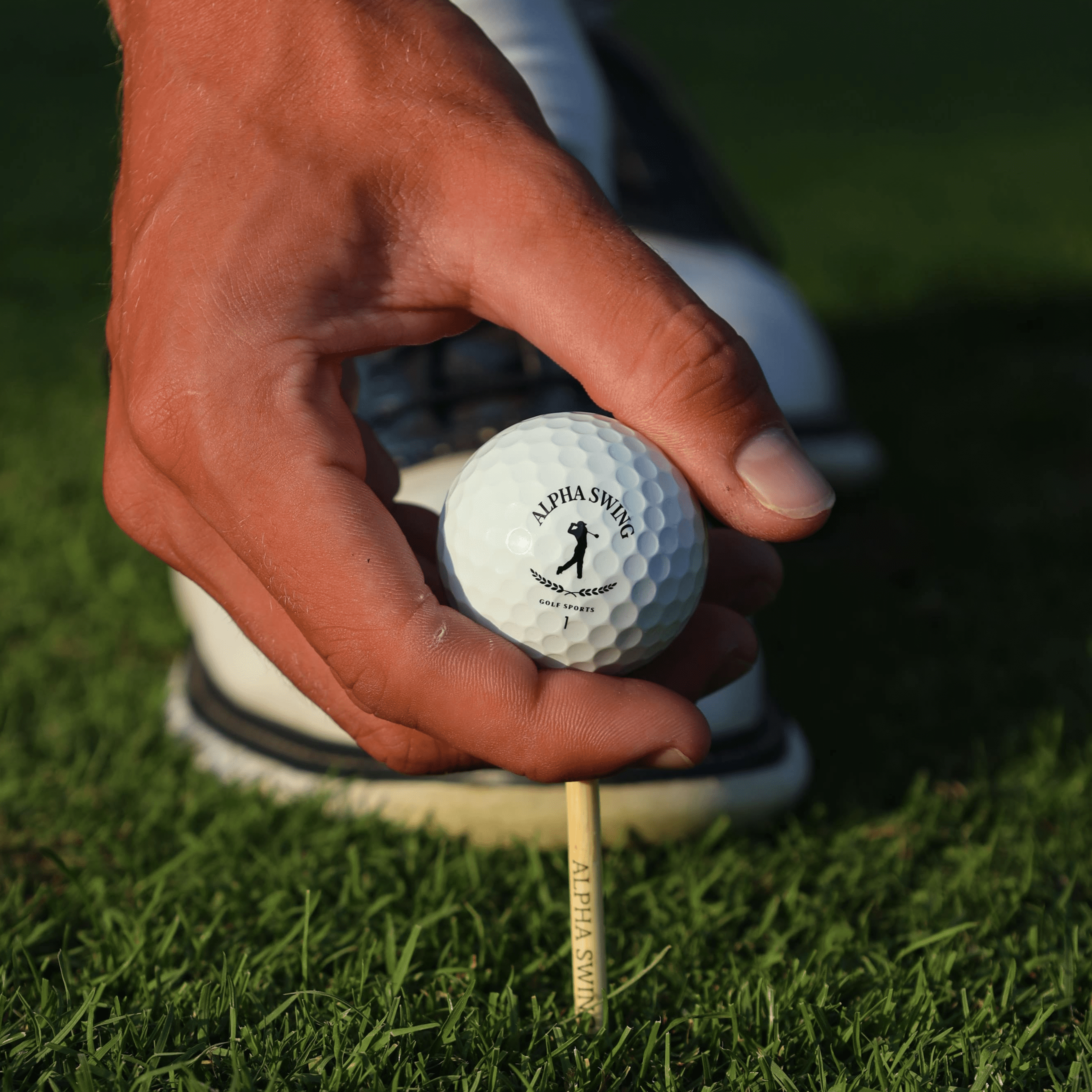 Detailaufnahme des Alpha Edition Golfballs und der Alpha Swing Tees. Hochwertige Golf-Ausrüstung für optimales Spiel und maximale Leistung auf dem Golfplatz.