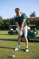 Männliches Model schlägt einen Golfball, während es das forest-grüne Alpha Swing Polo trägt. Ideal für stilvolle und funktionale Golfbekleidung