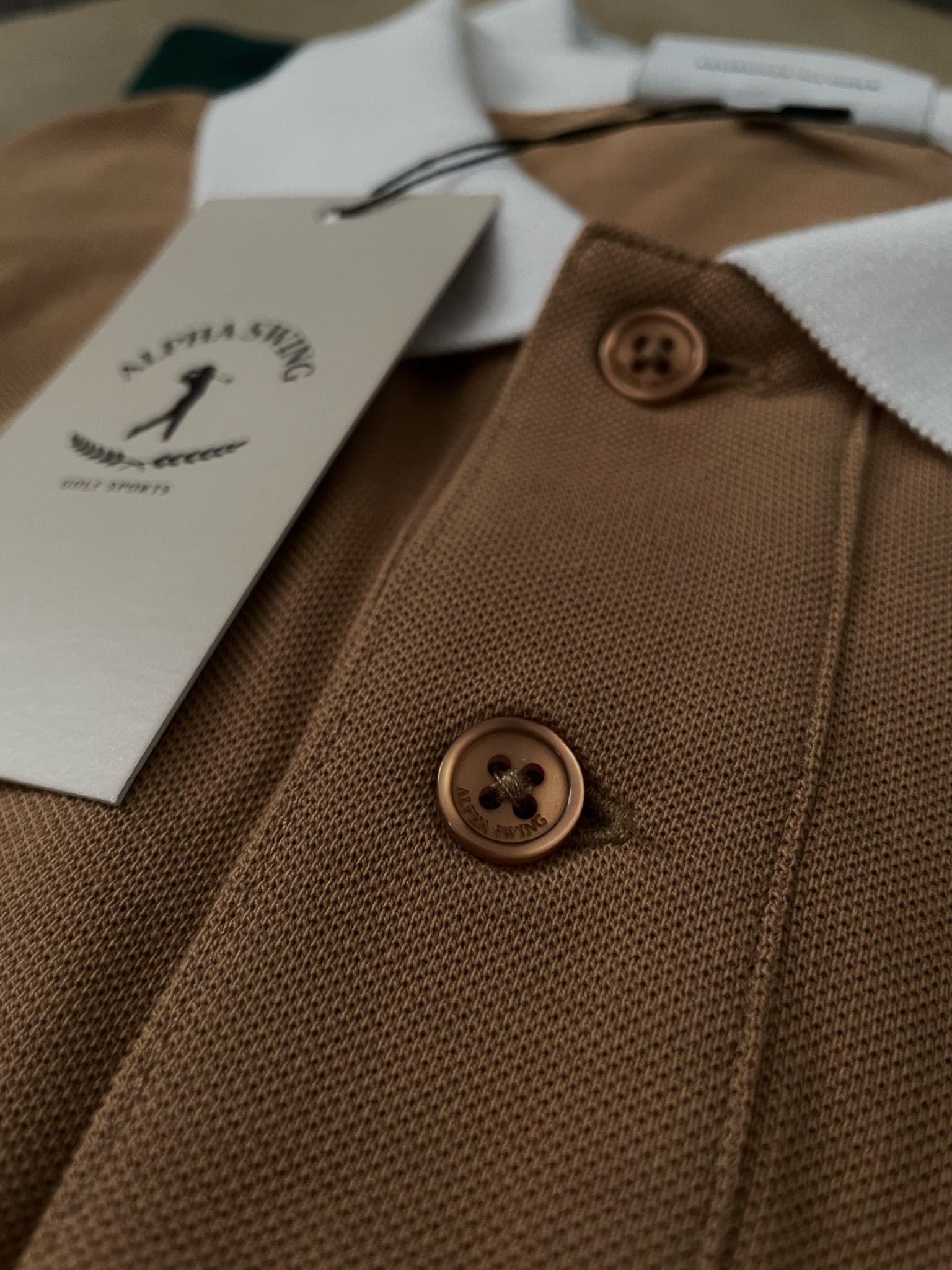 Detailaufnahme des sandbeigen Alpha Swing Polo-Shirts. Hochwertiges Golfbekleidungsstück.